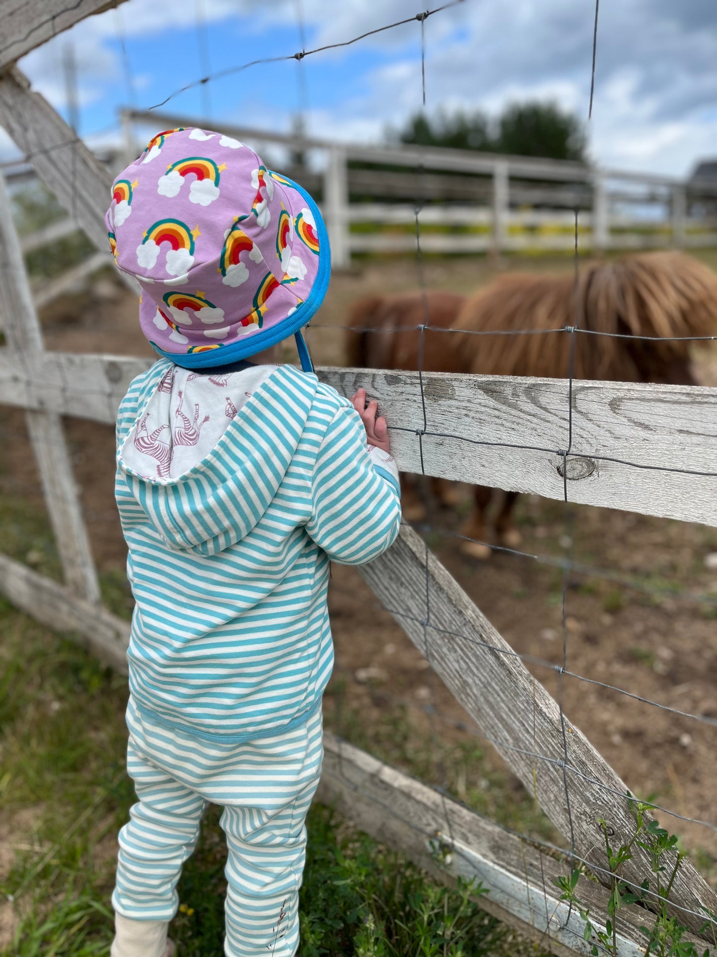 Stilingas dvipusis vaikiškas džemperis. Viena pusė margint zebrais, kita pusė žalsvai mėlynais dryžiukais. Su kapišonu.