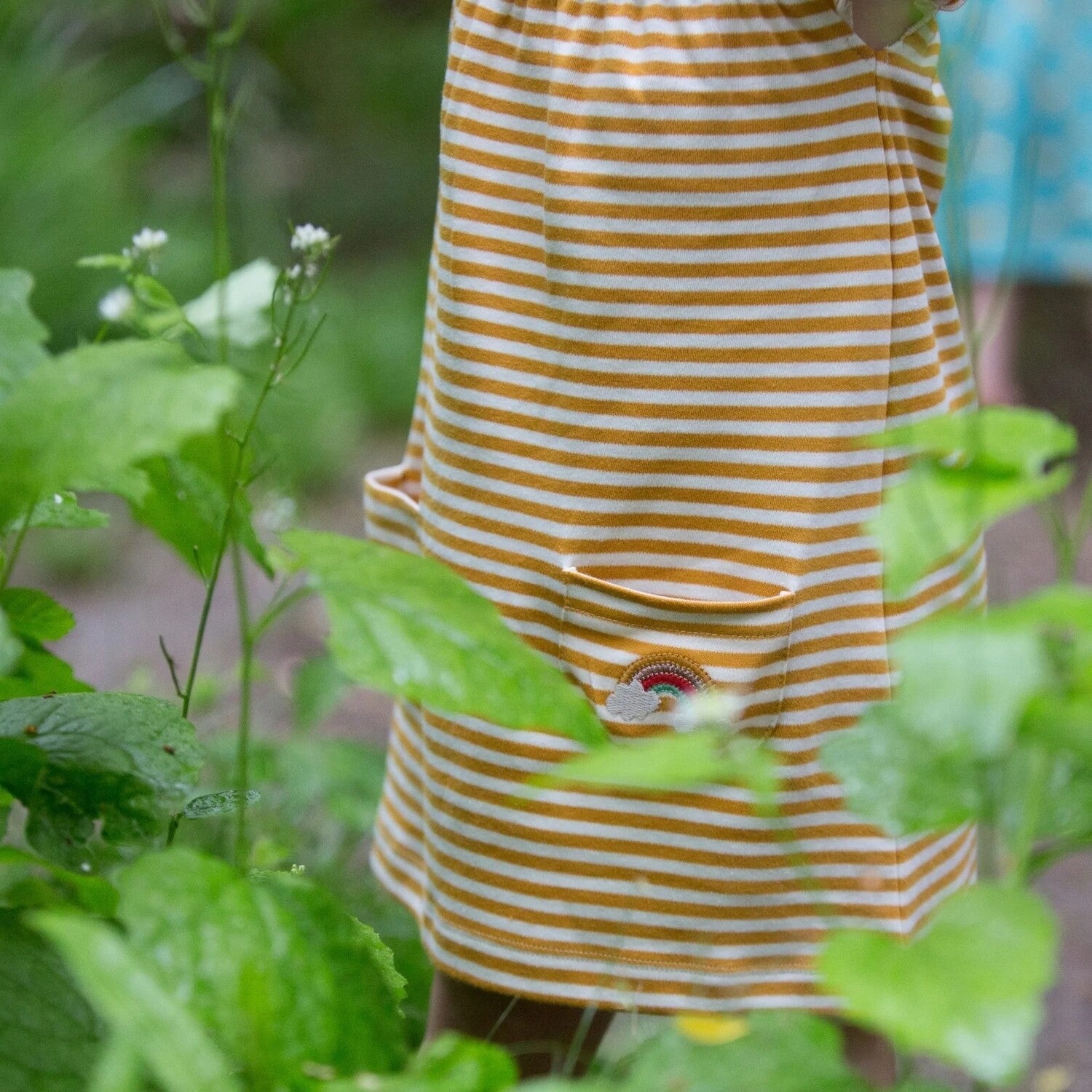 Vaikiška suknelės trumpomis rankovėmis iš medvilnės trikotažo. Geltona su dryžiukais, vaivorykštė ant kišenės.